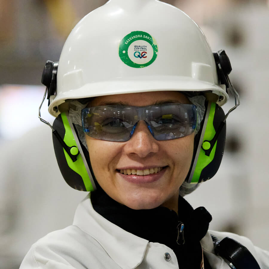female plant worker smiling with green ear protection and safety glasses